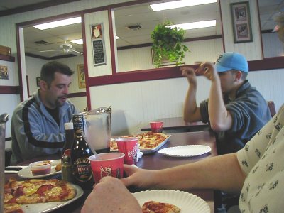 1997 Ford Taurus - A group of people are gathered around a table, enjoying pizza and beverages in a casual dining setting.