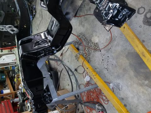 1996 Ford Bronco - A vehicle frame is suspended by chains and an engine hoist, undergoing restoration.