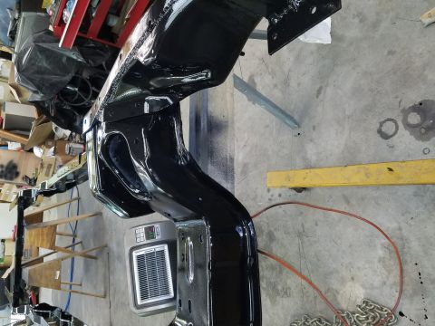 1996 Ford Bronco - A black painted vehicle frame is shown in a workshop setting, possibly undergoing restoration or repair.