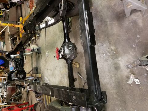 1996 Ford Bronco - The underside of a vehicle frame and rear axle assembly is visible in a workshop setting.