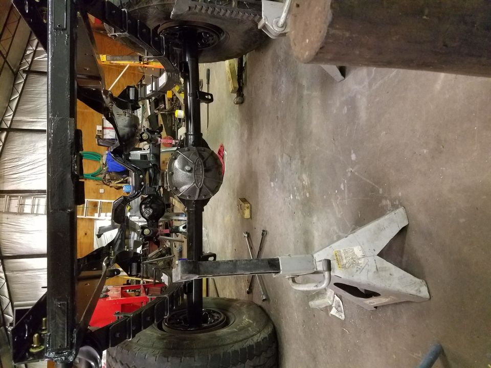 Vehicle frame with suspension components, axles, and tires on jack stands