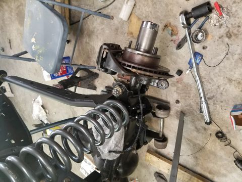 1996 Ford Bronco - Disassembled vehicle suspension parts are laid out on a concrete floor with tools.