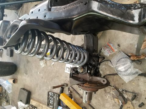 1996 Ford Bronco - Close-up view of vehicle suspension parts, including a coil spring and frame components, on a concrete floor.