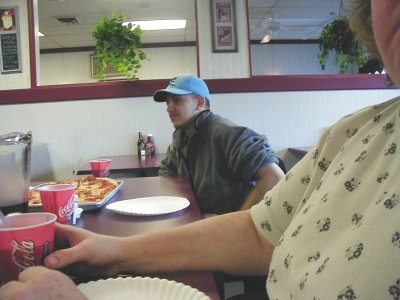 1997 Ford Taurus - Two people are seated at a table in a restaurant, with a pizza and drinks in front of them.