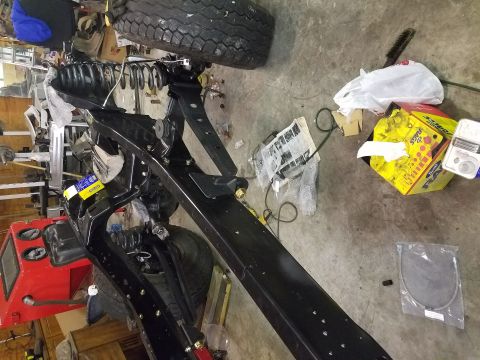 1996 Ford Bronco - Workshop scene with vehicle frame and suspension parts, along with various boxes and tools.