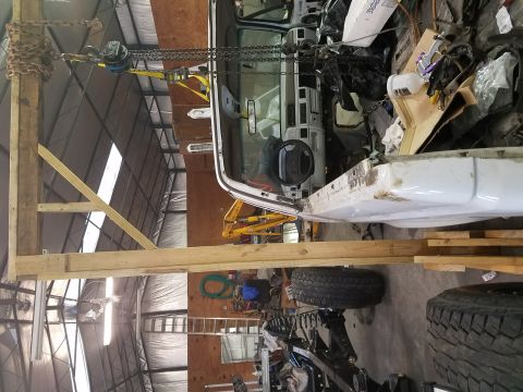 1996 Ford Bronco - The interior of a white truck cab is seen from the side, suspended by chains in a workshop.