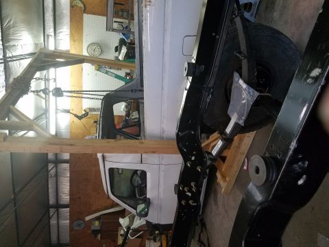 1996 Ford Bronco - 1996 Ford Bronco chassis and cab in a workshop, likely undergoing repairs or restoration.