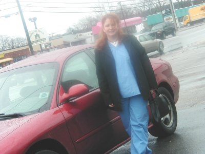 1997 Ford Taurus - Red 1997 Ford Taurus sedan with a woman in scrubs standing beside it on a wet day.