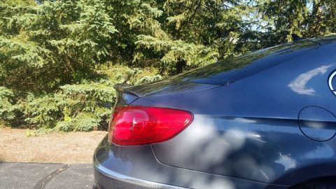 2010 Volkswagen Passat - A dark gray car with a subtle rear spoiler is parked outdoors.