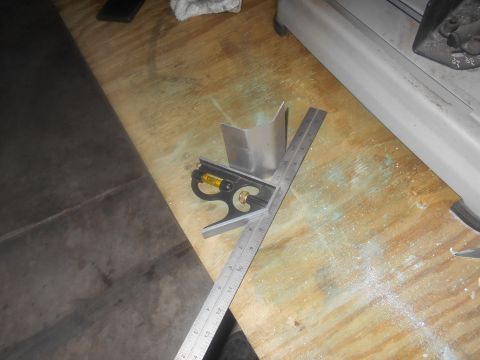 1992 Ford Bronco - A metal bracket is measured with a ruler and combination square on a workbench.