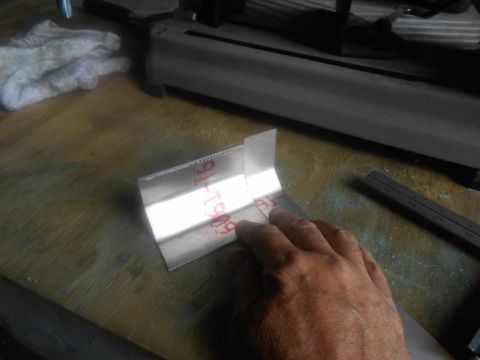 1992 Ford Bronco - A metal bracket with red markings is being held by a hand, with a cutting tool and ruler visible in the background.