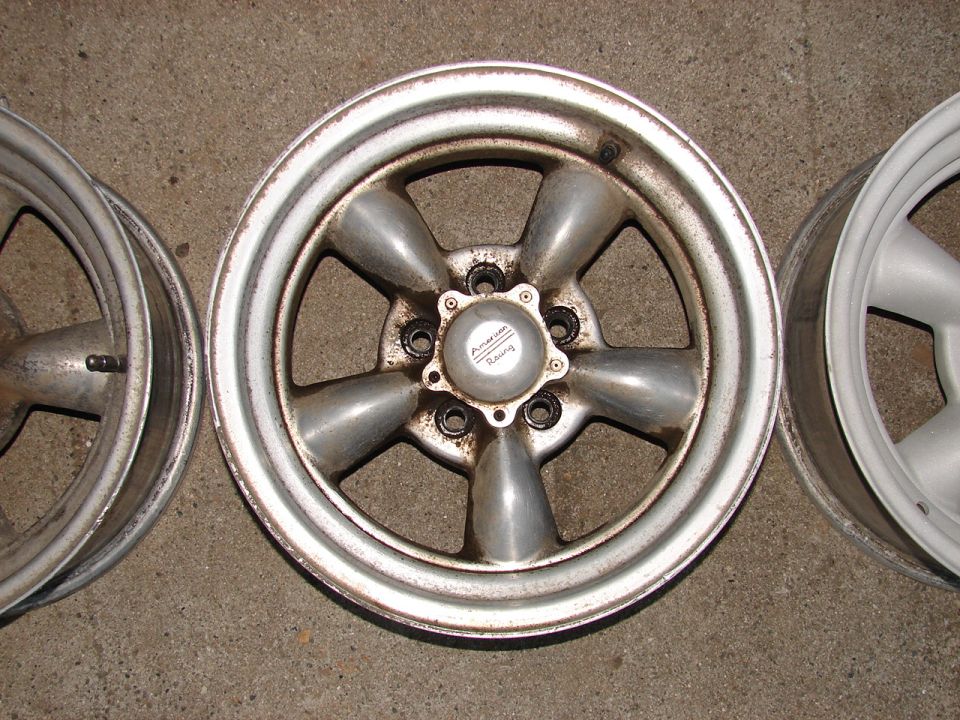 Three aluminum alloy wheels, one with 'American Racing' center cap