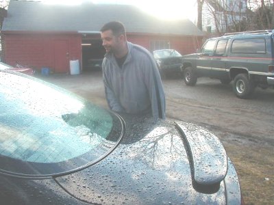 1997 Ford Taurus - A man stands next to a car, with a large SUV and another vehicle visible in the background.
