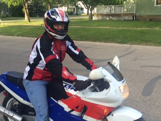 1989 Honda CBR600F - A rider is seated on a white and blue motorcycle, wearing a helmet and riding gear.