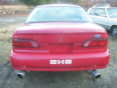1997 Ford Taurus - Rear view of a red 1997 Ford Taurus SHO sedan with dual exhaust pipes and a visible SHO badge.