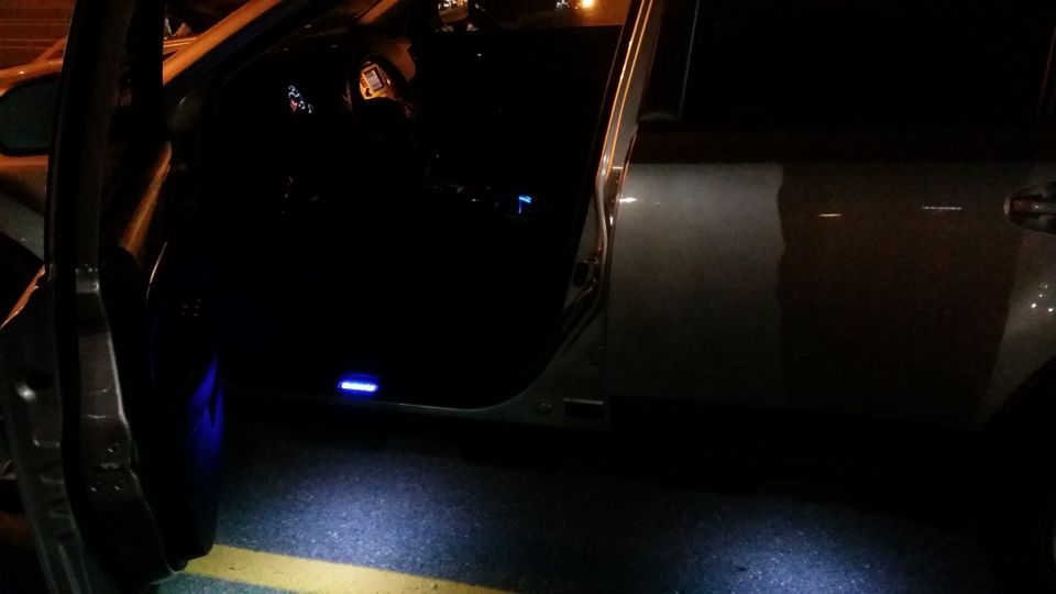 Car door open at night, showing illuminated door sill and interior