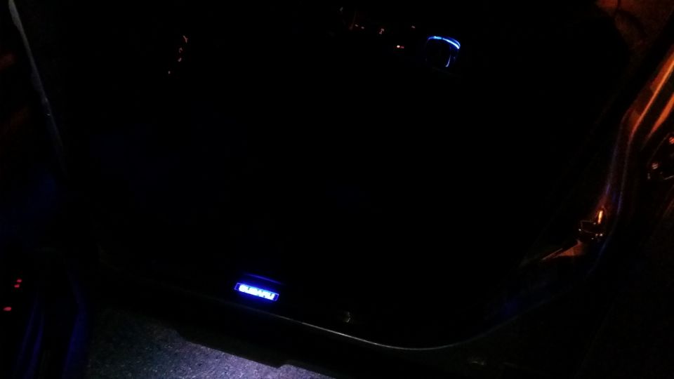 Blue illuminated Subaru logo on a car's interior door panel