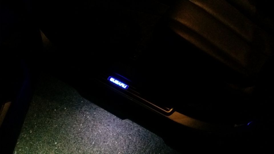 Illuminated Subaru door sill glowing blue inside a dark vehicle interior