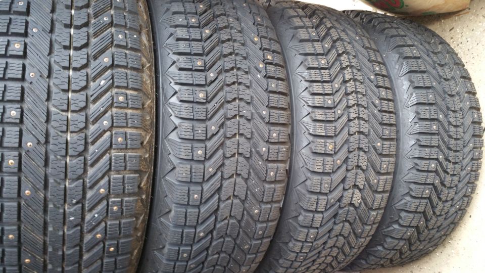Four studded winter tires lined up. Tread patterns vary slightly