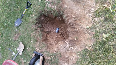 2007 Subaru Impreza - A hole dug in the grass reveals a discarded can, with gardening tools nearby.