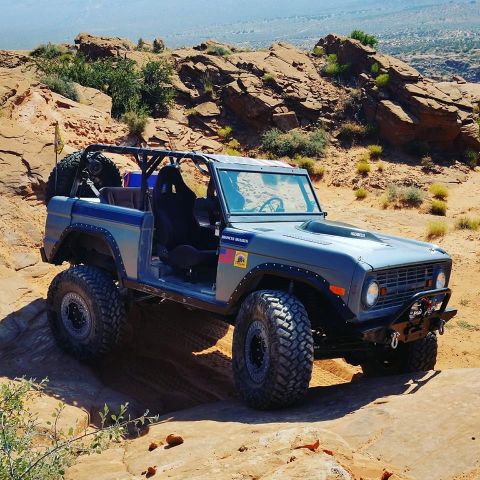 1979 Ford Bronco - This modified 1979 Ford Bronco navigates a challenging off-road course under a clear sky.