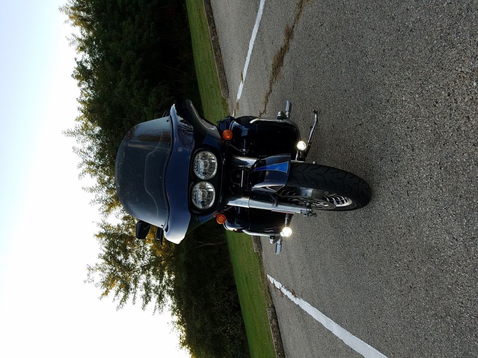 Dark blue touring motorcycle with dual headlights and a large windshield parked on asphalt