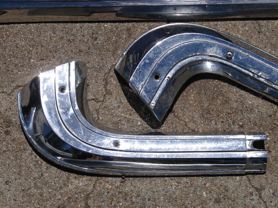 two curved chrome trim pieces and a straight one on concrete