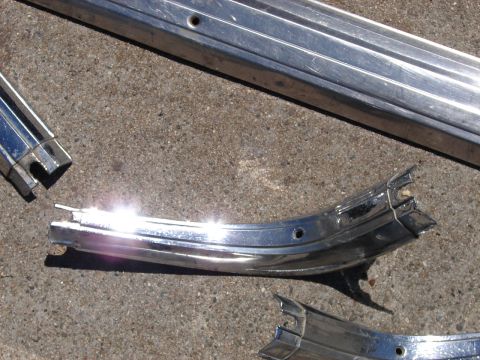 1973 Ford Ranchero - Broken chrome trim pieces scattered on a concrete surface.