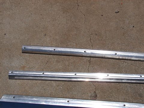 1973 Ford Ranchero - Three aluminum trim pieces with multiple drilled holes are shown resting on a concrete surface.