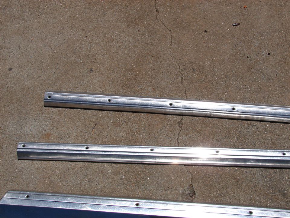 Three aluminum trim pieces with drilled holes on concrete
