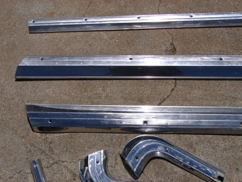 1973 Ford Ranchero - Chrome trim pieces, possibly for a classic car, are displayed on a cracked concrete ground.