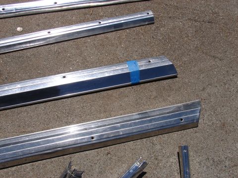 1973 Ford Ranchero - Several aluminum trim pieces are laid out on a concrete surface, with one piece marked by blue tape.