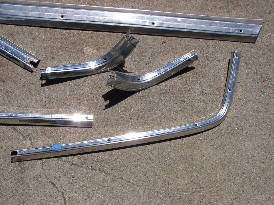 Chrome trim pieces on concrete, including curved and straight sections with visible screw holes