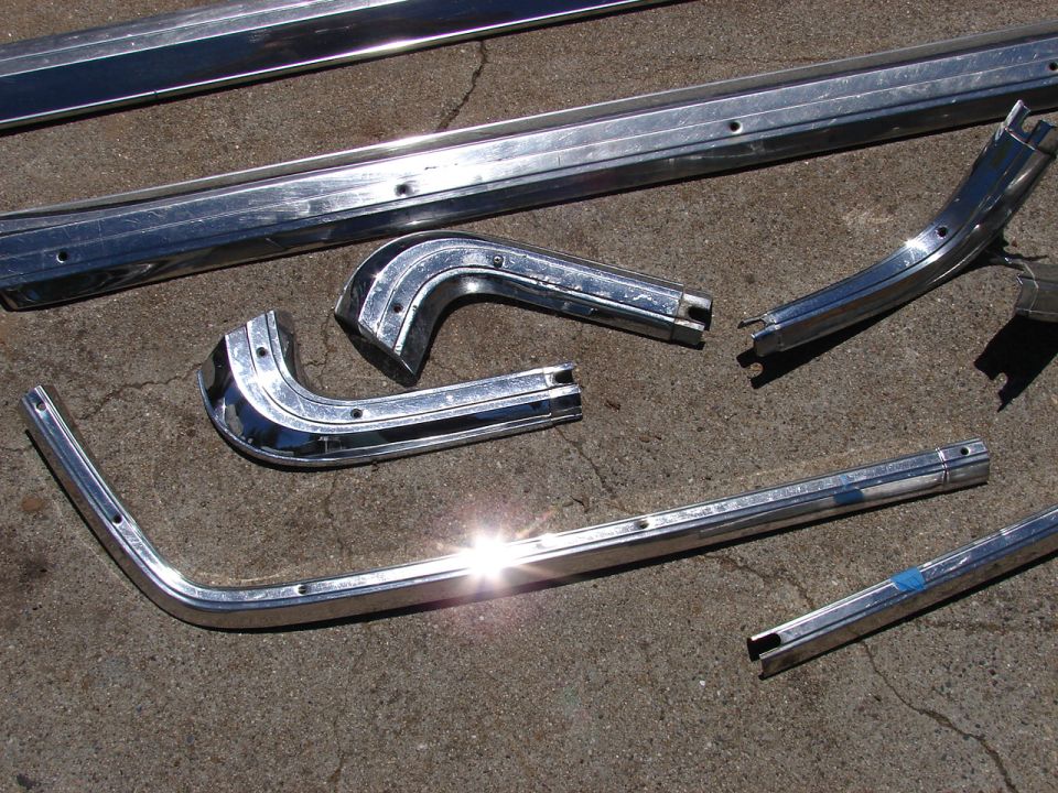 Several chrome trim pieces, some curved, laid out on concrete