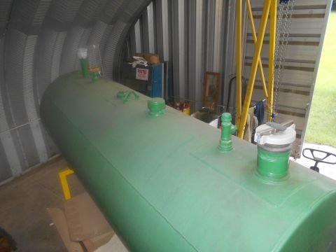 1992 Ford Bronco - A large green storage tank sits inside a metal building, with a yellow crane structure visible in the background.