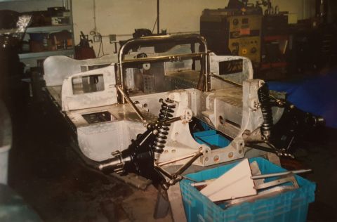1973 Ford Mustang - This image shows the bare aluminum chassis and suspension of a vehicle under construction in a workshop setting.