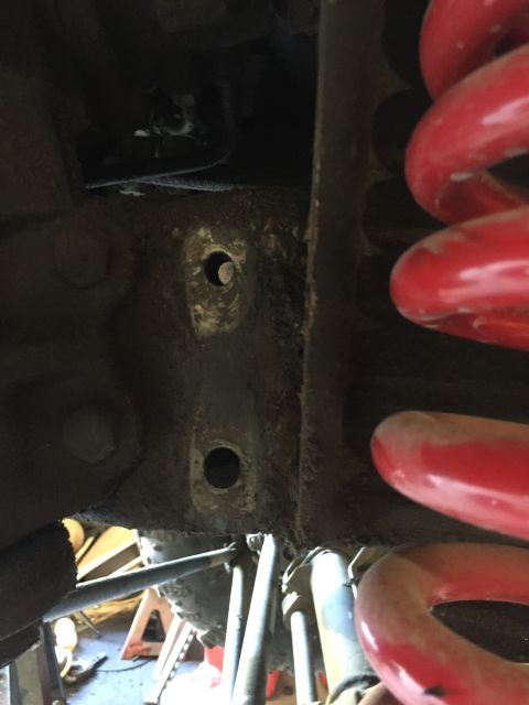 1979 Ford Bronco - Undercarriage view of suspension components, including red coil springs and metal brackets.