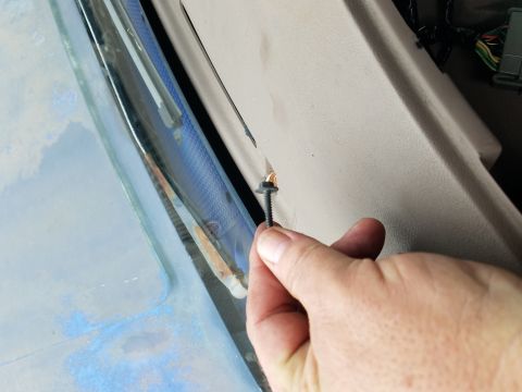 1994 Ford Bronco - A hand is shown removing a screw from the interior dashboard trim of a vehicle.