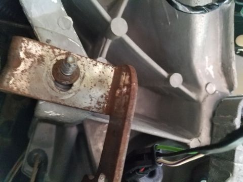 1994 Ford Bronco - Close-up of a rusted metal bracket and a wiring harness, likely from a vehicle's interior.