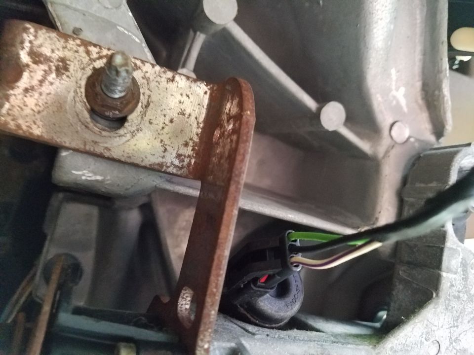Wiring harness connector with multiple colored wires plugged into a black rubber grommet on a metal housing