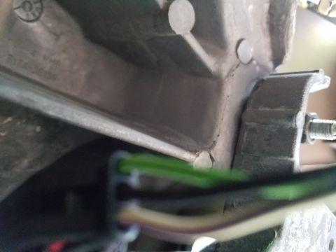 1994 Ford Bronco - A close-up view shows a vehicle's wiring harness connected to a metal bracket, with some text visible on the metal part.