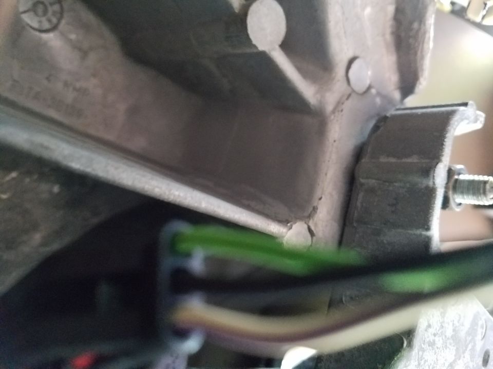 Close-up of green and white wires connected to a metal bracket on a vehicle