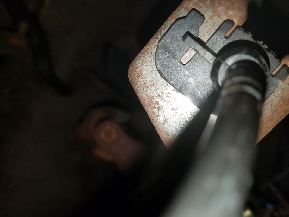 Close-up of rusty metal bracket with a black plastic piece and a metal rod