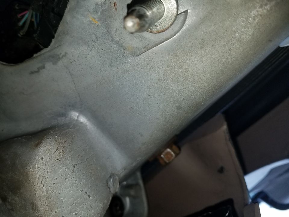 Close-up of a metal bracket with wires and a bolt in a vehicle's interior