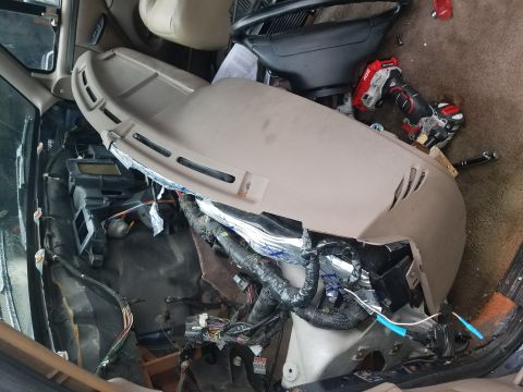 1994 Ford Bronco - The interior of a vehicle shows a disassembled dashboard with exposed wiring and insulation, with a power drill on top.