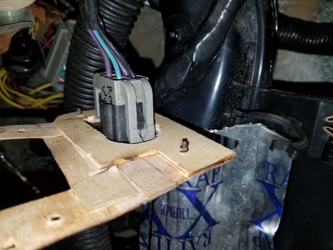 1994 Ford Bronco - Close-up of a vehicle's interior wiring harness connector, mounted on a makeshift wooden bracket.