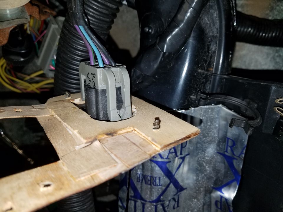 Wiring harness connector with purple, blue, and black wires attached to a wooden bracket