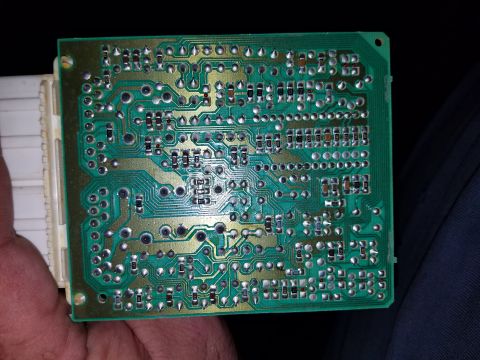1994 Ford Bronco - A close-up view of a green circuit board with a white connector attached.