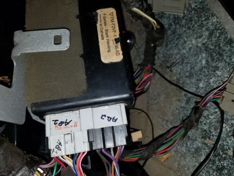 1994 Ford Bronco - Close-up of a vehicle's electronic control module and wiring harness, with a label indicating 'F-Series - Black Housing'.