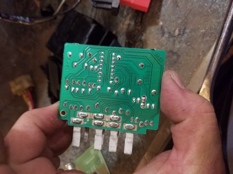 1994 Ford Bronco - A person holds a green circuit board with visible solder points and pins, showing some printed text.